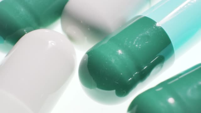 close up of multi colored medicine capsules pills over white background.