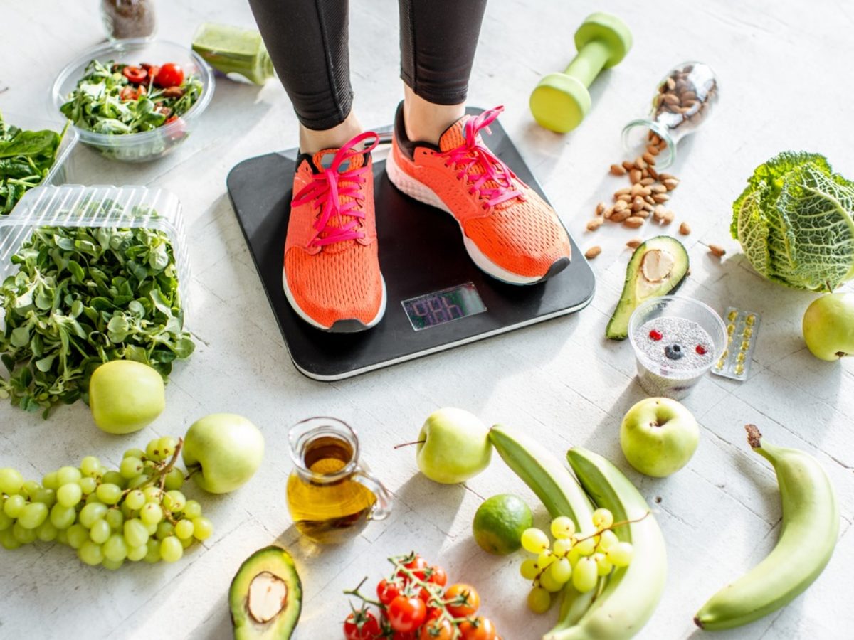 sports woman weighing with healthy food around