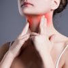 sore throat, woman with pain in neck, gray background