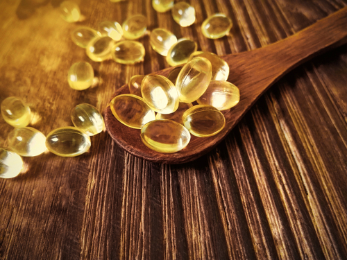 vitamin,d,yellow,pills,on,wood,spoon,on,wooden,background